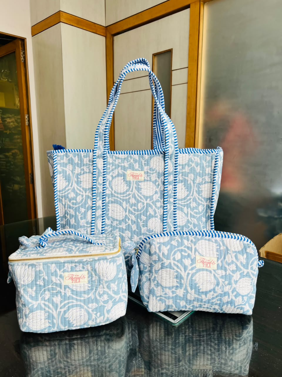 Set of blue patterned bags on a reflective surface with a blurred background